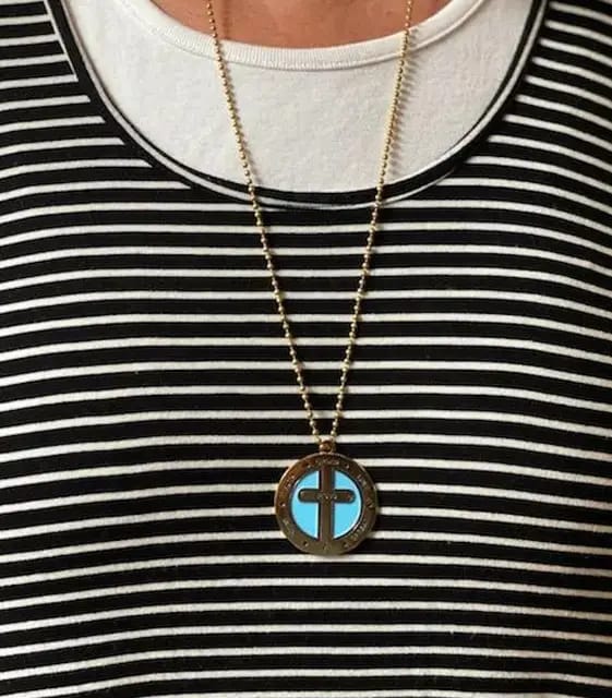 A person wearing a necklace with a cross on it.