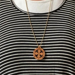 A person wearing a necklace with a wooden cross on it.