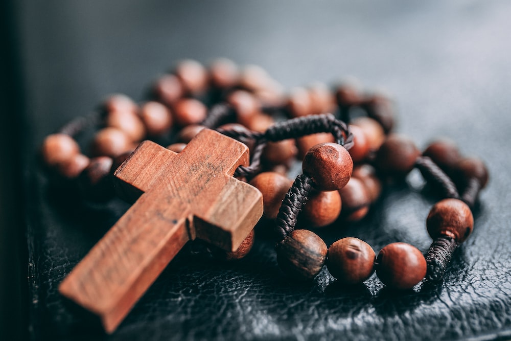 A wooden cross and rosary beads on a table.